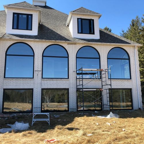 Large windows being installed on a home exterior with scaffolding